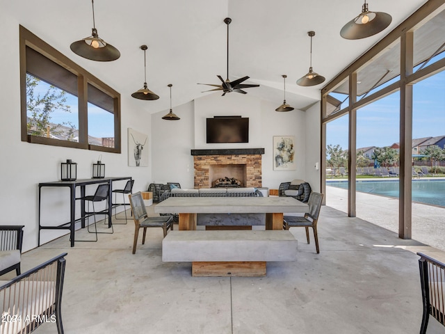 dining space featuring concrete flooring, a fireplace, vaulted ceiling, and a healthy amount of sunlight