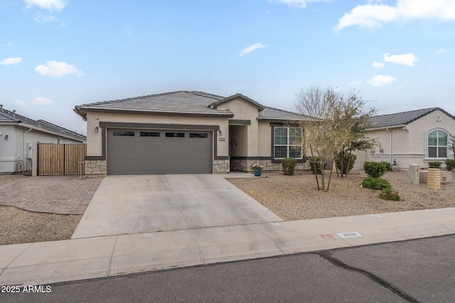 view of front of property with a tiled roof, an attached garage, stone siding, and driveway
