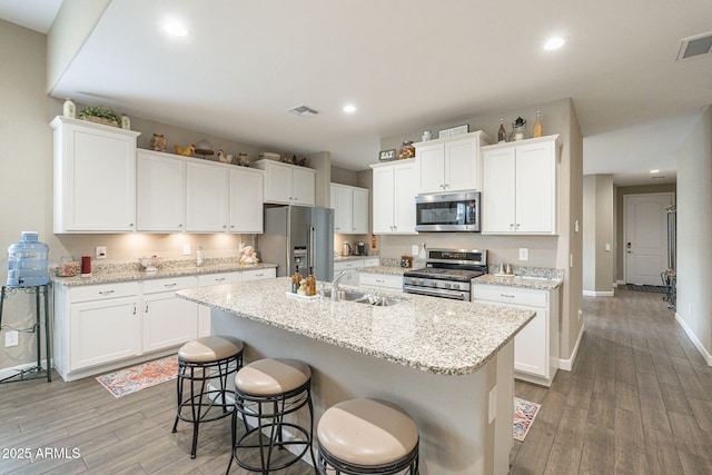 kitchen featuring a sink, stainless steel appliances, visible vents, and white cabinetry