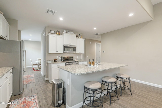 kitchen with light wood-style flooring, white cabinets, appliances with stainless steel finishes, and a kitchen island
