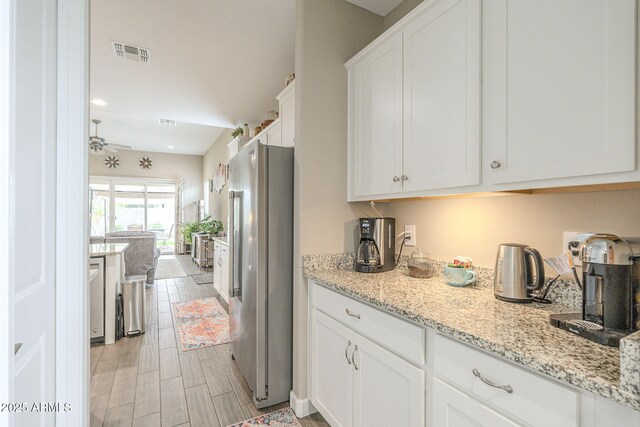 kitchen featuring light stone counters, visible vents, light wood finished floors, white cabinets, and appliances with stainless steel finishes