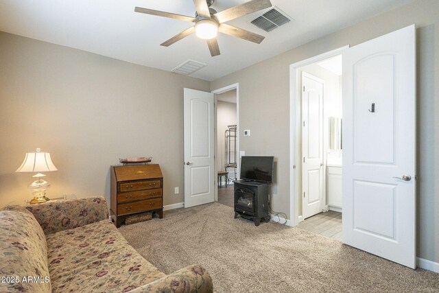 living area featuring visible vents, carpet flooring, ceiling fan, and a wood stove