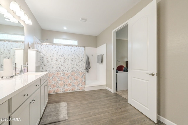 bathroom featuring visible vents, wood finished floors, a shower with shower curtain, baseboards, and vanity