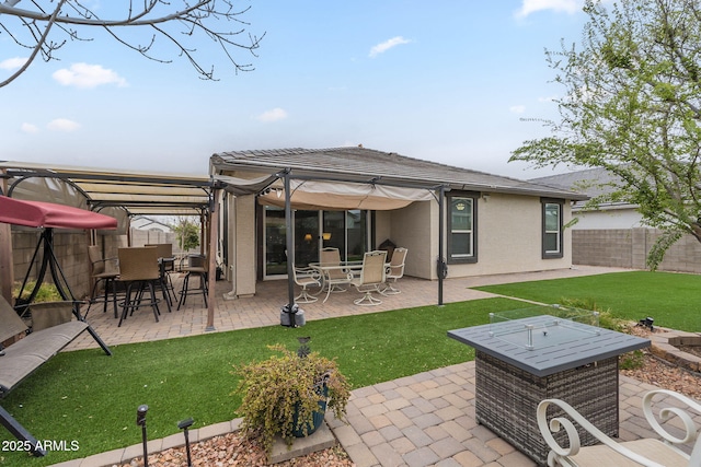 rear view of property with fence, a pergola, stucco siding, a patio area, and a lawn