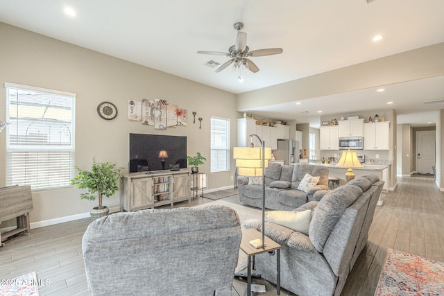 living area featuring a ceiling fan, visible vents, light wood-type flooring, and baseboards