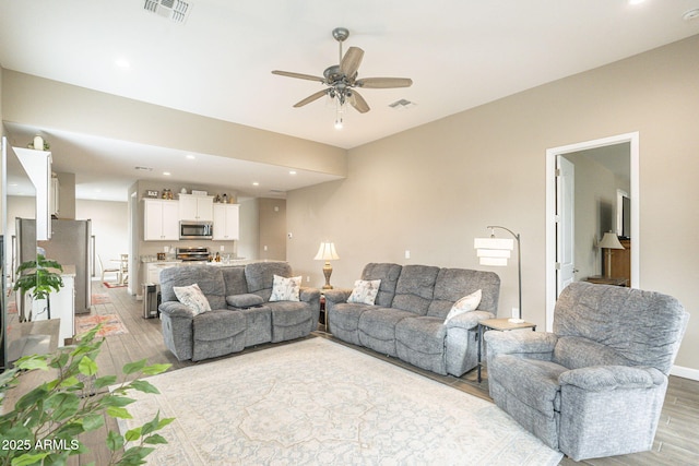 living area featuring light wood-style flooring, recessed lighting, a ceiling fan, and visible vents