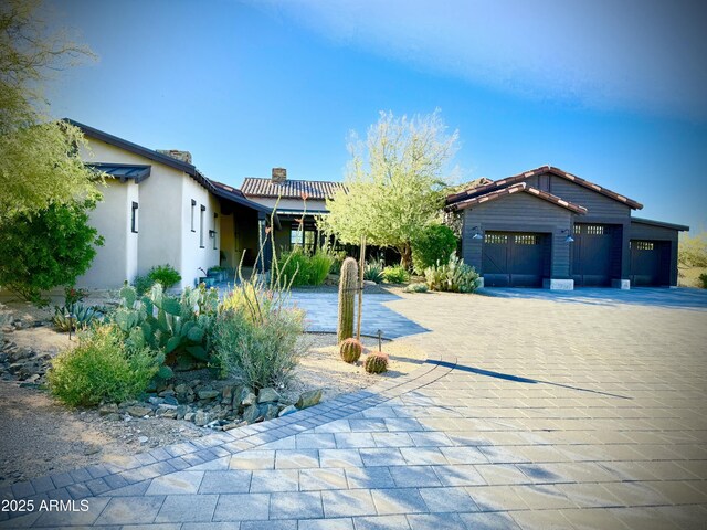 8555 E Tecolote Cir, Scottsdale, AZ 85266 - view of front of property featuring decorative driveway, a garage, a chimney, and stucco siding