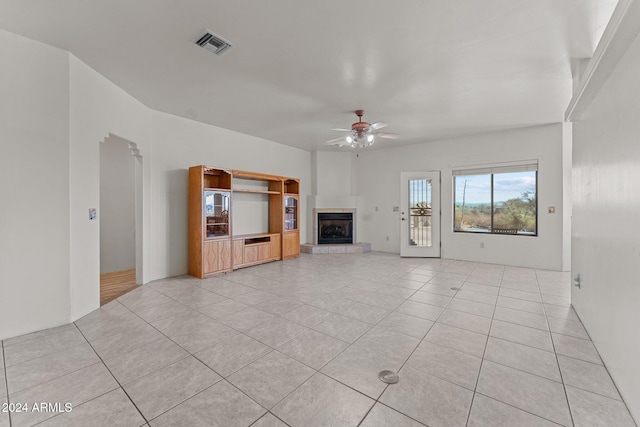 unfurnished living room featuring ceiling fan, a tile fireplace, and light tile patterned floors