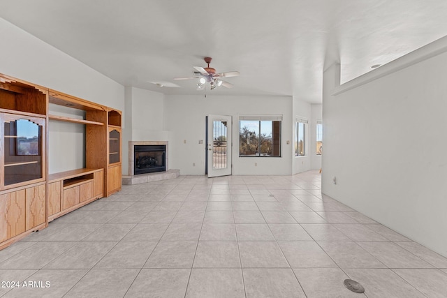 unfurnished living room with ceiling fan, a tile fireplace, and light tile patterned floors