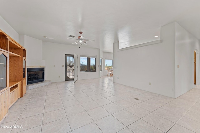 unfurnished living room featuring light tile patterned flooring, ceiling fan, and a tile fireplace