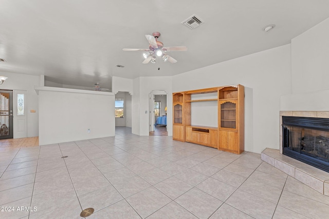 unfurnished living room with light tile patterned flooring, ceiling fan, and a tile fireplace