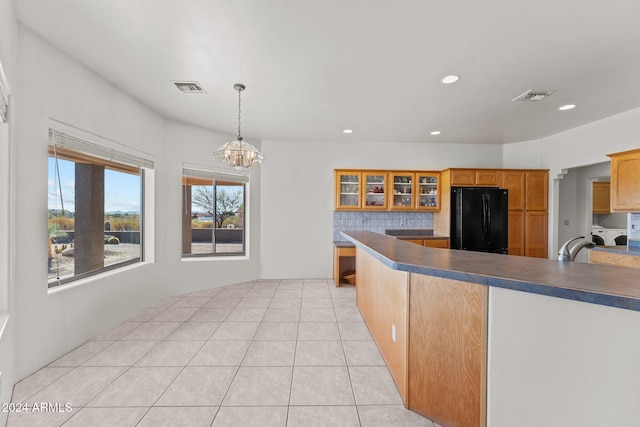 kitchen featuring light tile patterned flooring, black fridge, backsplash, decorative light fixtures, and a notable chandelier