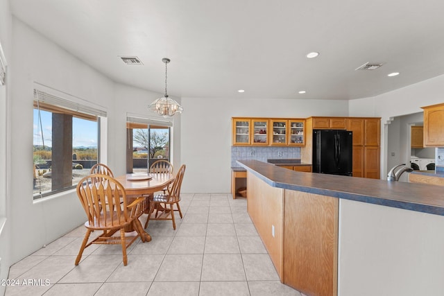 kitchen featuring tasteful backsplash, black fridge, hanging light fixtures, and plenty of natural light