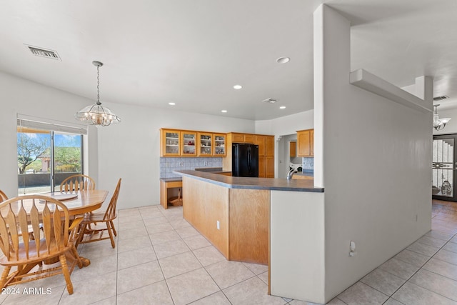 kitchen with black refrigerator, backsplash, hanging light fixtures, and an inviting chandelier