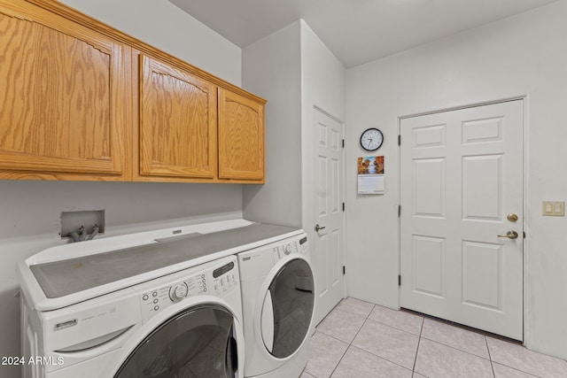 washroom with cabinets, washing machine and clothes dryer, and light tile patterned floors