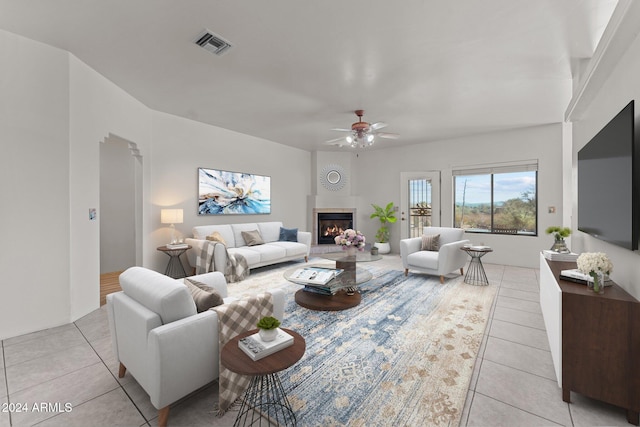 tiled living room with a fireplace and ceiling fan