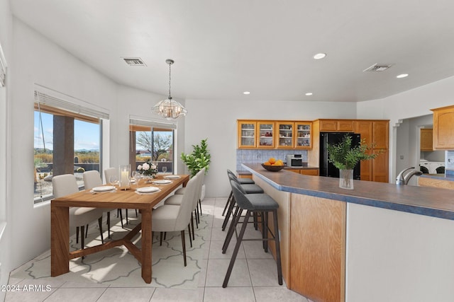 kitchen with black fridge, light tile patterned floors, an inviting chandelier, decorative light fixtures, and decorative backsplash