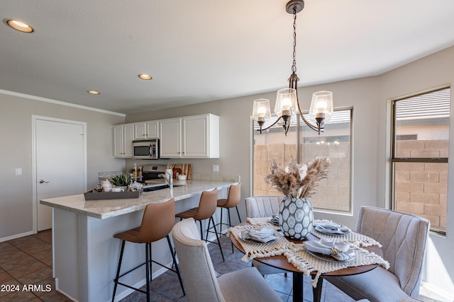 kitchen featuring hanging light fixtures, light stone counters, white cabinetry, ornamental molding, and stainless steel appliances