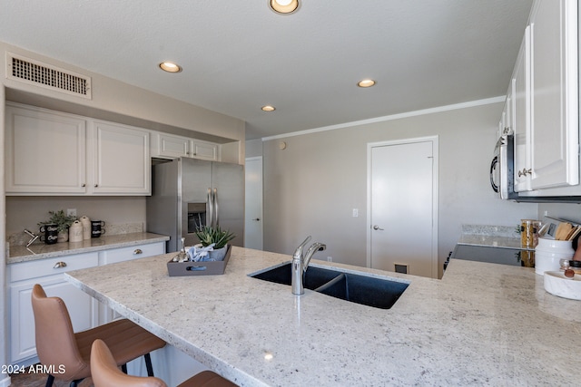 kitchen with stainless steel appliances, sink, a breakfast bar area, and white cabinets