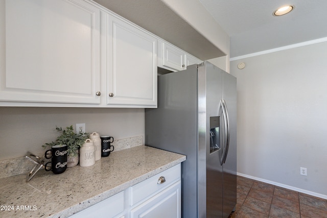 kitchen featuring light stone countertops, stainless steel fridge with ice dispenser, white cabinetry, and dark tile patterned floors