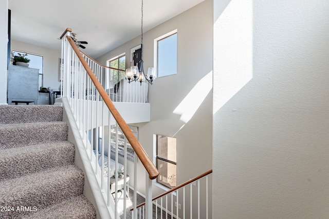 staircase featuring ceiling fan with notable chandelier