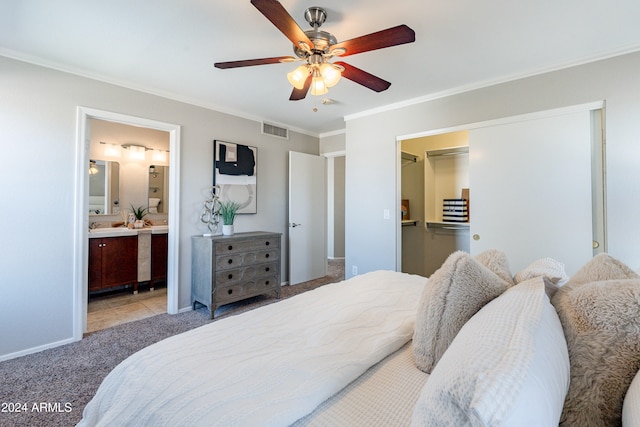 carpeted bedroom featuring ornamental molding, ensuite bathroom, and ceiling fan