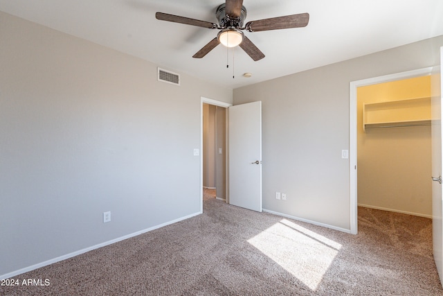 unfurnished bedroom featuring a spacious closet, carpet floors, a closet, and ceiling fan