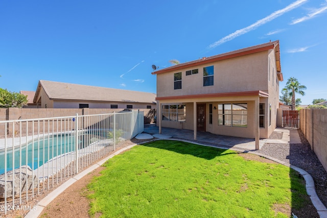 back of house with a fenced in pool, a patio area, and a lawn