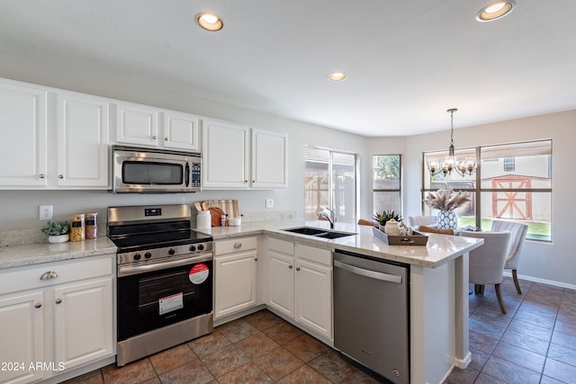 kitchen featuring kitchen peninsula, white cabinets, appliances with stainless steel finishes, an inviting chandelier, and pendant lighting