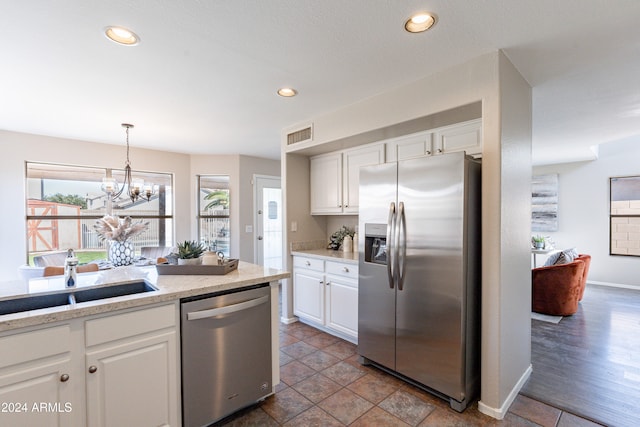 kitchen featuring white cabinetry, sink, a notable chandelier, decorative light fixtures, and stainless steel appliances