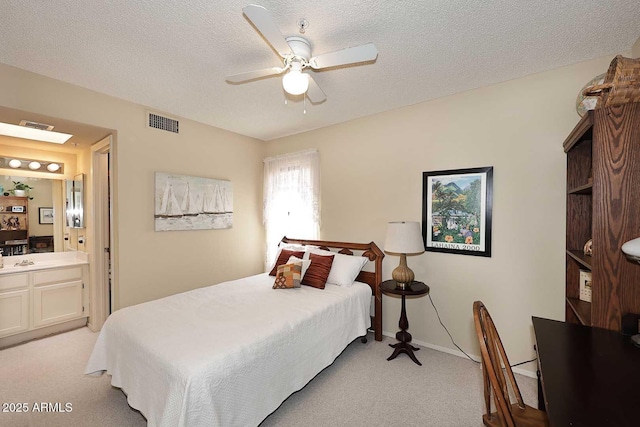 bedroom featuring visible vents, a textured ceiling, connected bathroom, and light colored carpet