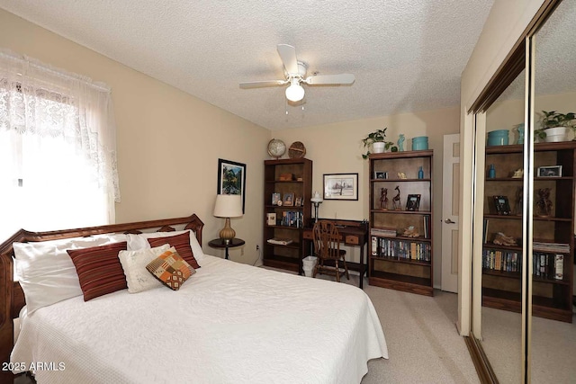 bedroom with a ceiling fan, light carpet, a closet, and a textured ceiling