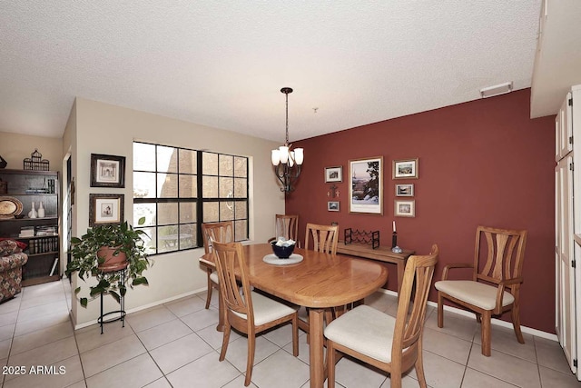 dining space with light tile patterned floors, baseboards, a textured ceiling, and a notable chandelier