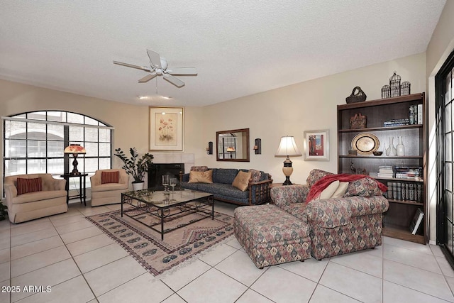 living room featuring light tile patterned floors, a ceiling fan, and a textured ceiling
