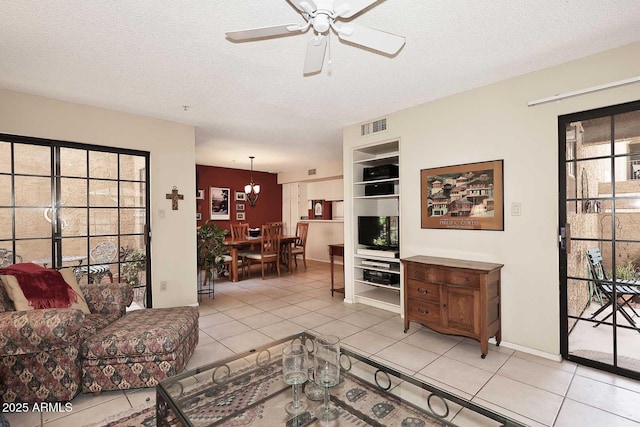 living area featuring light tile patterned floors, ceiling fan with notable chandelier, a textured ceiling, and visible vents