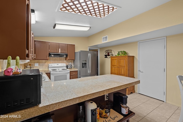 kitchen with stainless steel fridge, backsplash, light tile patterned floors, electric range, and lofted ceiling