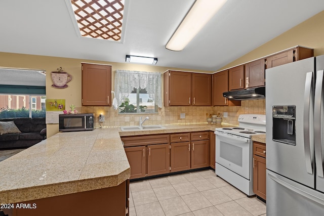 kitchen with decorative backsplash, stainless steel fridge, sink, and white electric stove