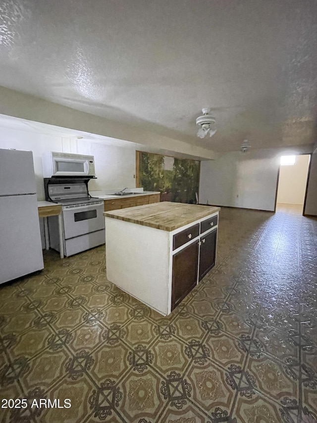 2995 W Rd 1 S, Chino Valley, AZ 86323 - kitchen with light countertops, a kitchen island, a textured ceiling, and white appliances