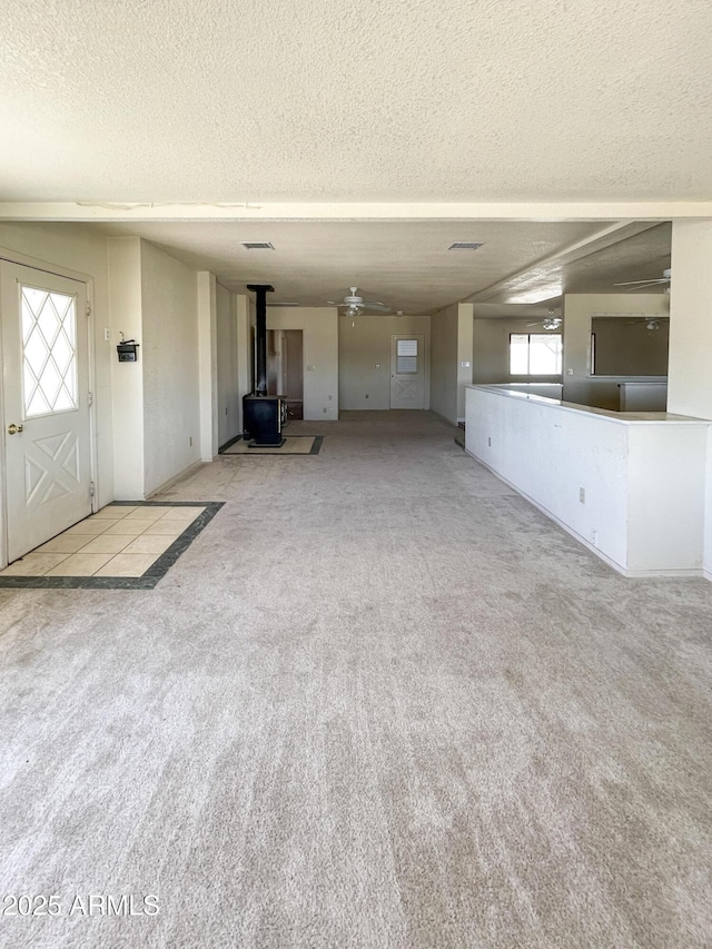 2995 W Rd 1 S, Chino Valley, AZ 86323 - unfurnished living room with carpet flooring, a wealth of natural light, a wood stove, and a textured ceiling