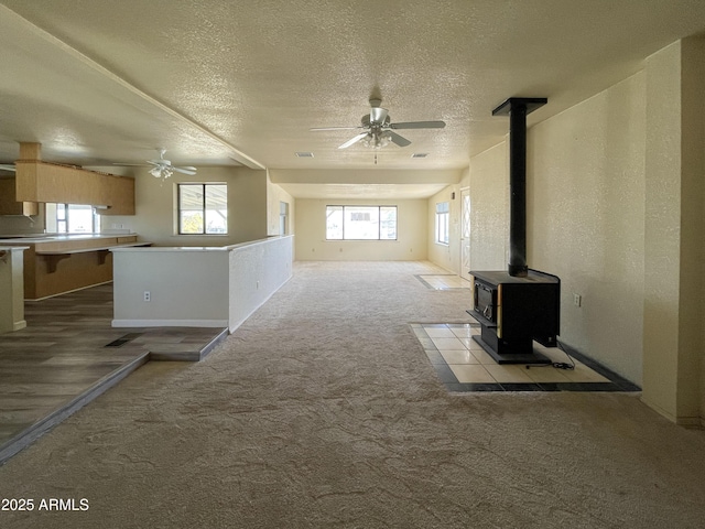 2995 W Rd 1 S, Chino Valley, AZ 86323 - unfurnished living room with carpet flooring, a wood stove, a ceiling fan, and a wealth of natural light