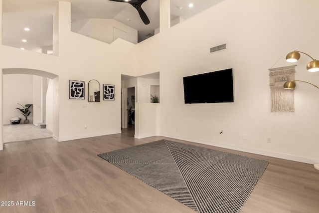 1421 E Charleston Ave, Phoenix, AZ 85022 - unfurnished living room with arched walkways, ceiling fan, wood finished floors, baseboards, and a high ceiling