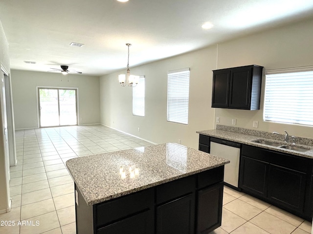 kitchen with ceiling fan with notable chandelier, sink, stainless steel dishwasher, light tile patterned floors, and a kitchen island