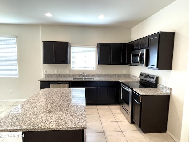 kitchen featuring light stone countertops, sink, light tile patterned floors, and stainless steel appliances