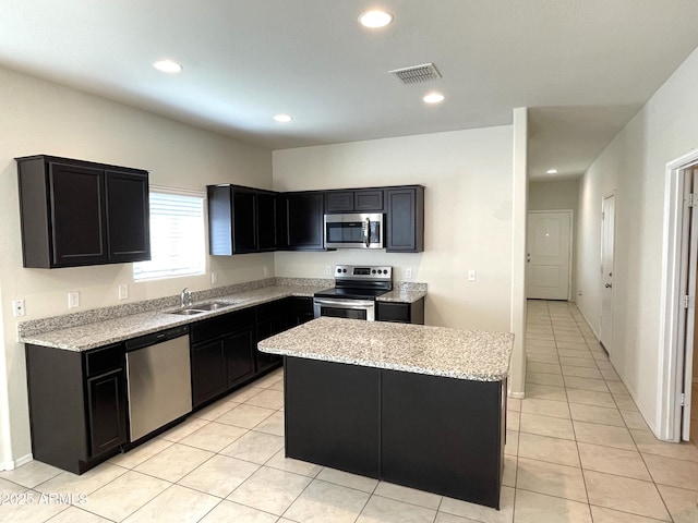 kitchen featuring light tile patterned floors, stainless steel appliances, a kitchen island, and sink