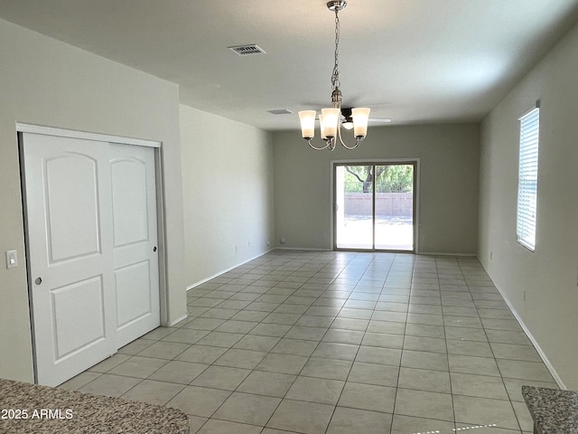 spare room with light tile patterned floors and a chandelier