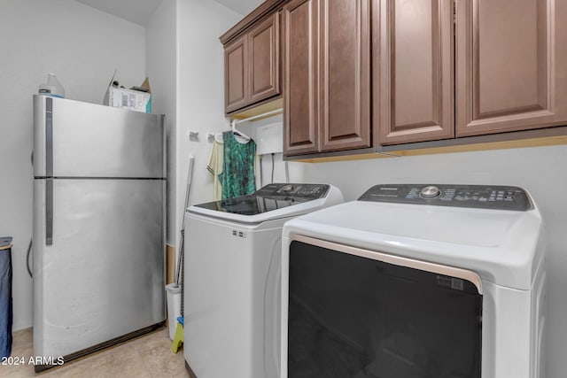 clothes washing area with cabinets and washing machine and dryer