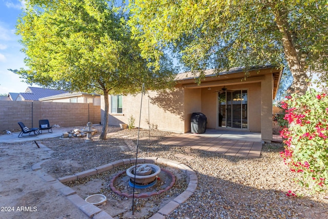 rear view of property featuring a fire pit, ceiling fan, and a patio area