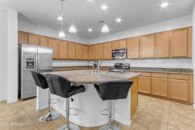 kitchen with pendant lighting, a breakfast bar area, light stone countertops, an island with sink, and stainless steel appliances