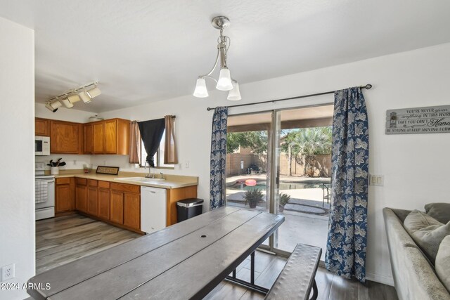 kitchen featuring white appliances, pendant lighting, rail lighting, and light hardwood / wood-style flooring