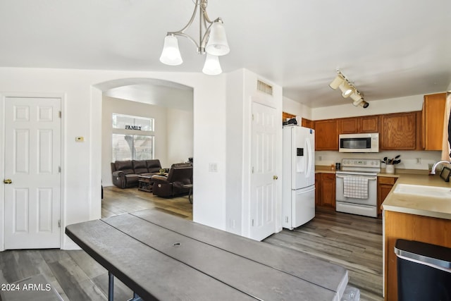 kitchen featuring decorative light fixtures, rail lighting, sink, dark hardwood / wood-style flooring, and white appliances